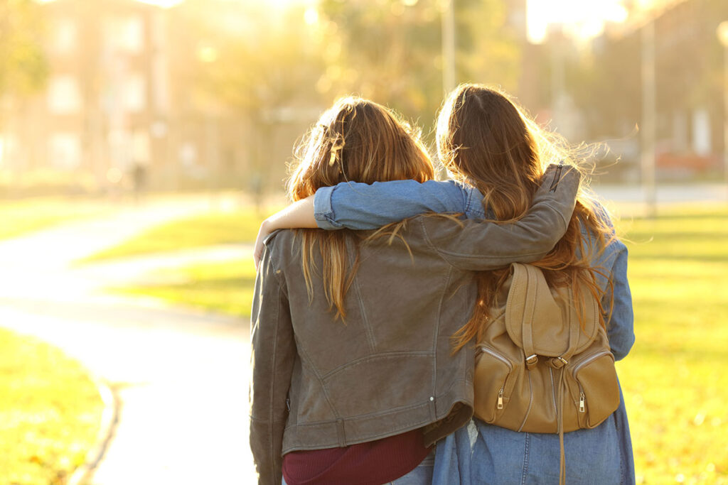 Affectionate friends walking at sunset in a park.