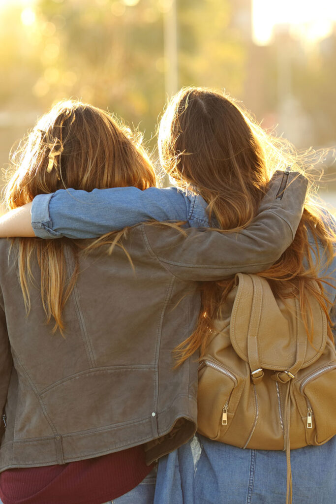 Affectionate friends walking at sunset in a park.